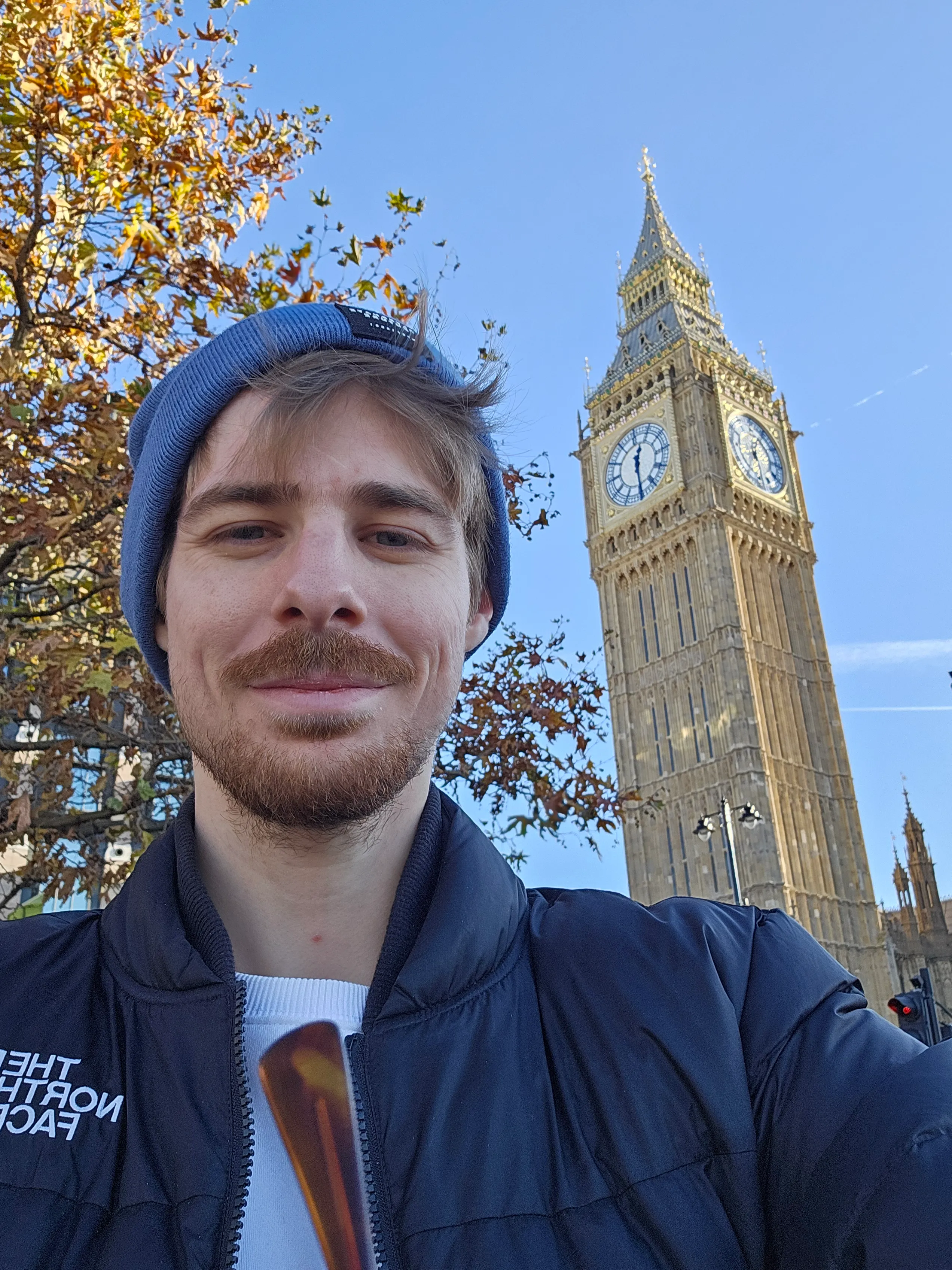 Rafa Audibert smiling with a blue beanie and a black jacket in front of the Big Ben in London, UK